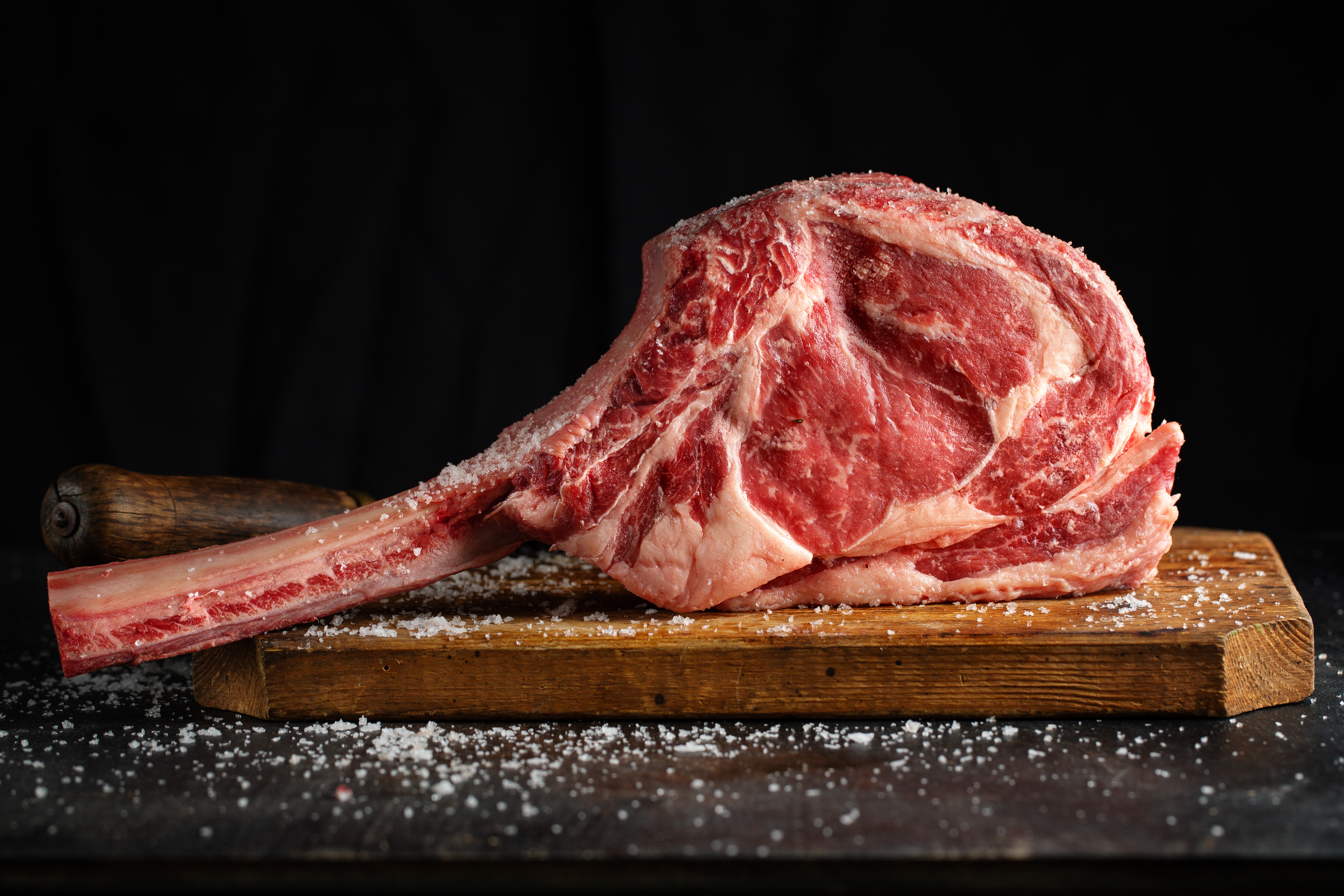 vers-vlees-tomahawk-steak-op-oude-houten-plank-donkere-achtergrond-detailopname
